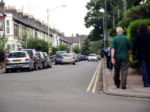 The north section of Tenison Road is straight with a sharp bend. Parked cars dominate the streetscape.
